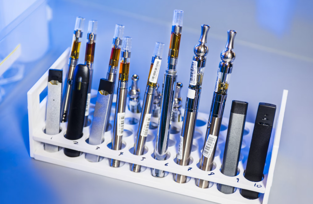 Vape pens and disposable vapes lined up in a test tube rack