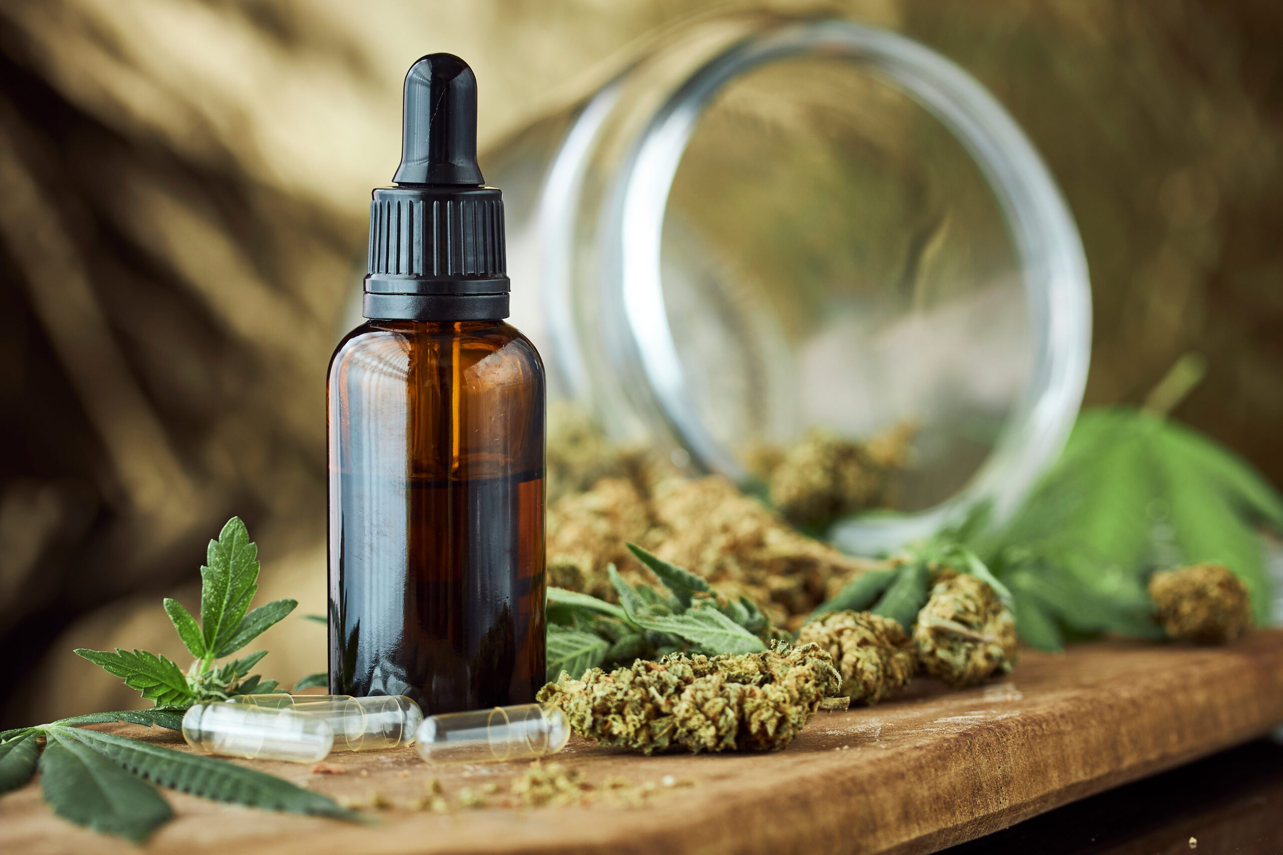 Tincture bottle sitting beside a spilled jar of marijuana flowers