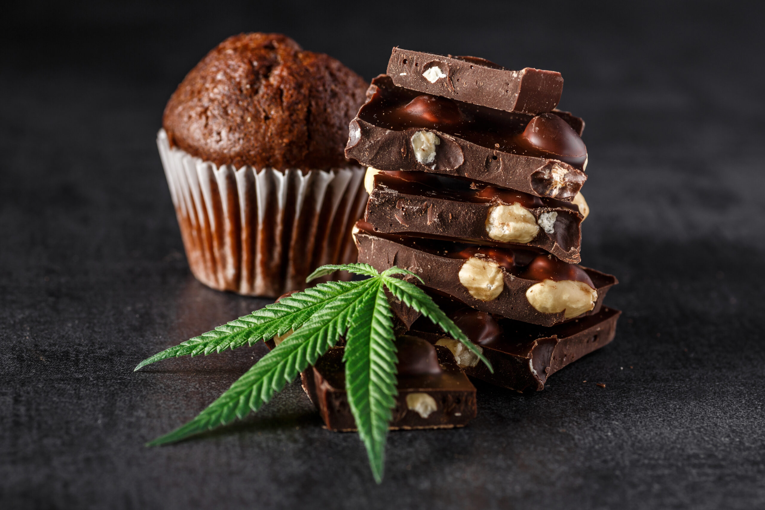 Muffin and sliced chocolate bar sit beside a marijuana leaf